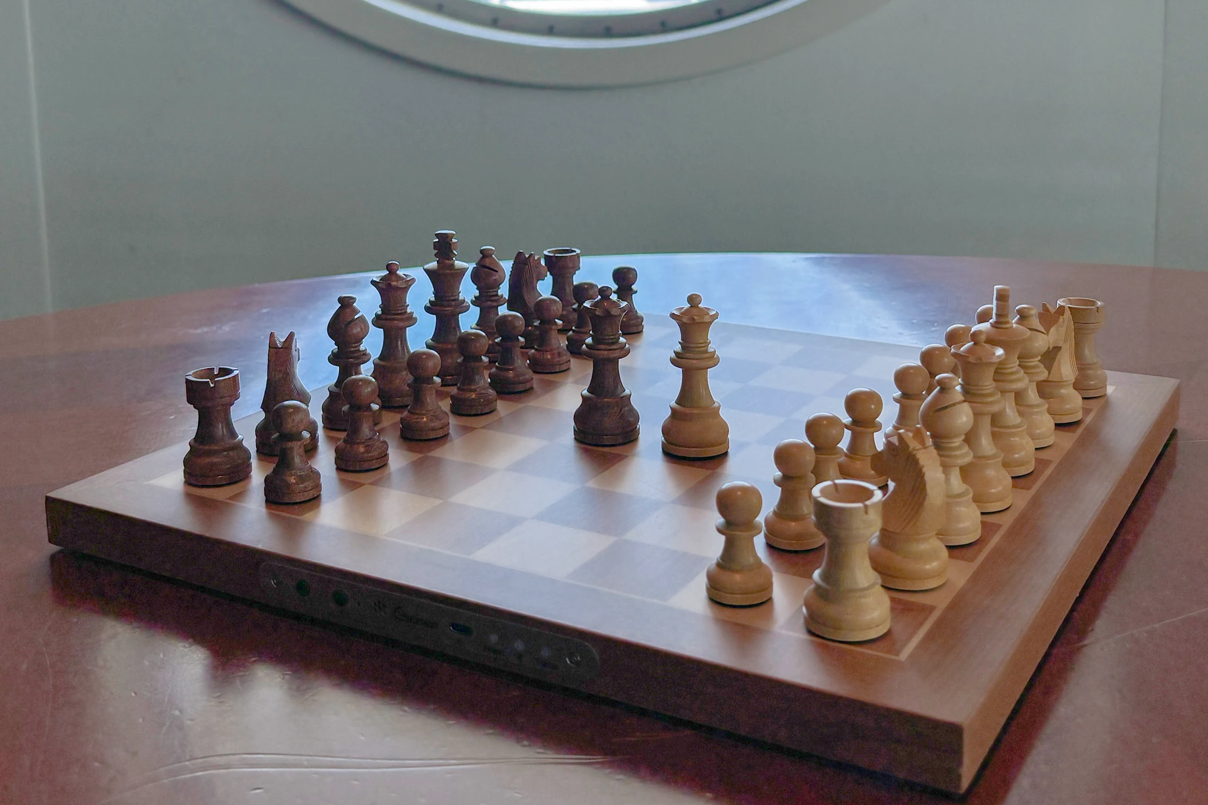 Chessnut Air Plus у иллюминатора — доска и деревянные фигуры крупным планом